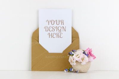 Blank postcard mockup with craft paper envelope and white flowers