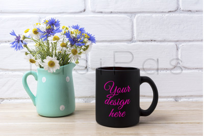 Black coffee mug mockup with cornflower and daisy in pitcher