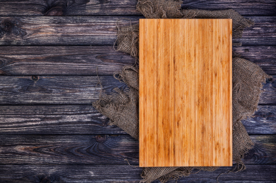 Cutting board on dark wood background, top view