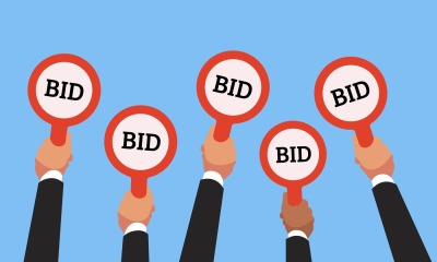 Buyers hands raising auction bid paddles with numbers of competitive p