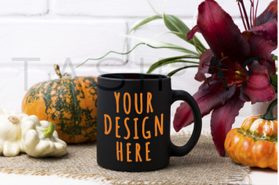 Black coffee mug mockup with pumpkin and red lily.