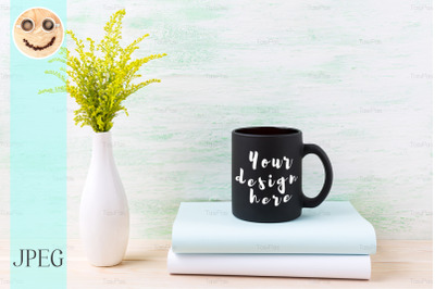 Black coffee mug mockup with ornamental green grass and books.