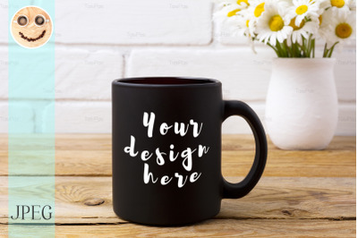 Black coffee mug mockup with chamomile bouquet in rustic vase.