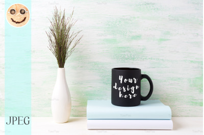 Black coffee mug mockup with dark meadow grass in vase and books.