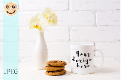 White coffee mug mockup with soft yellow orchid in vase and cookies