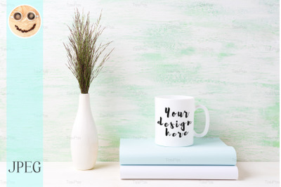 White coffee mug mockup with dark meadow grass in vase and books