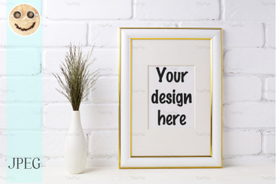 Gold decorated frame mockup with dark grass in vase near brick wall