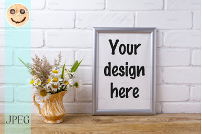 Silver frame mockup with chamomile and grass in golden pitcher