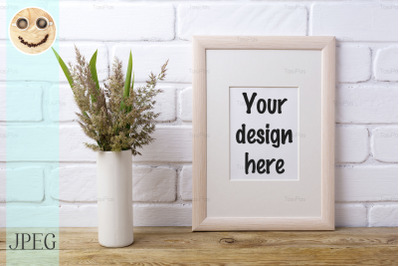 Wooden frame mockup with grass and green leaves in cylinder vase