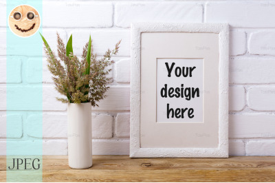 White frame mockup with grass and green leaves in cylinder vase