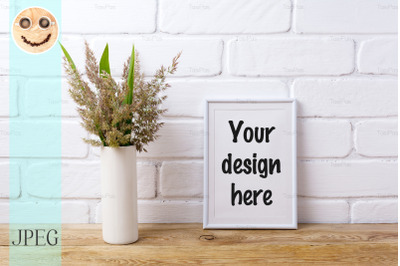 White frame mockup with  grass and green leaves in cylinder vase