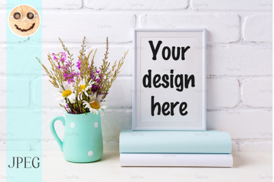 White frame mockup with chamomile and purple flowers in mint green pit
