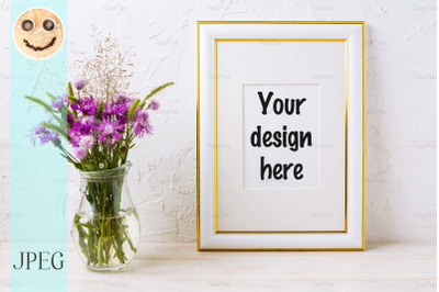 Gold decorated frame mockup with purple burdocks in glass