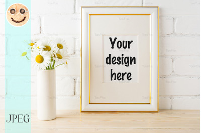 Gold decorated frame mockup with daisy near painted brick wall