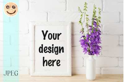 White frame mockup with purple campanula bouquet near brick wall