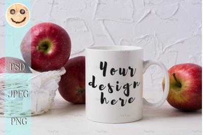 White coffee mug mockup with red apples in wicker basket