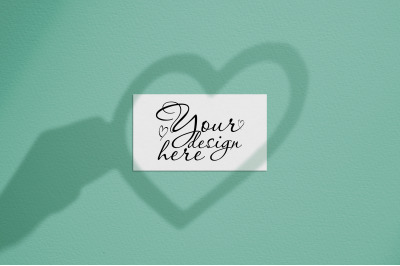 Business card mock up with shadows heart in hand on emerald background