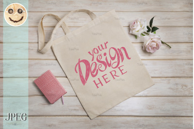 Tote bag mockup with roses and notepad.