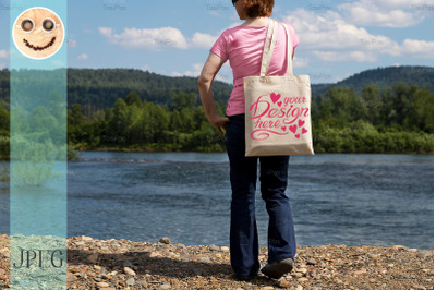 Woman holding tote bag mockup, river bank