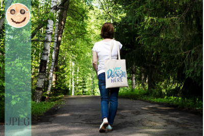 Woman in the park holding tote bag mockup.