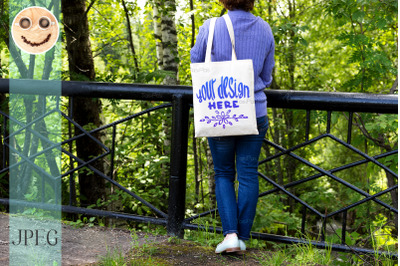 Woman in blue jumper holding tote bag mockup