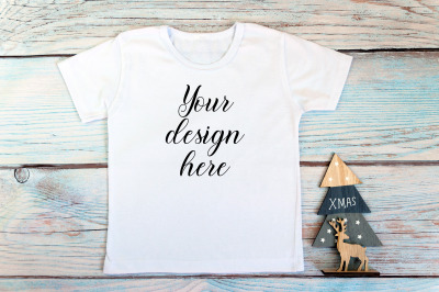 Kids Christmas White T-shirt mockup on a wooden background.