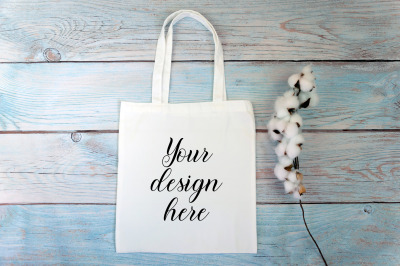 White tote bag Mockup with cotton flowers on a wooden background.