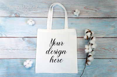 White tote bag Mockup with cotton flowers on a wooden background.