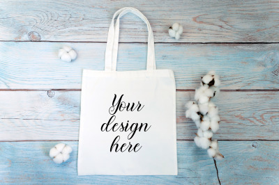 White tote bag Mockup with cotton flowers on a wooden background.