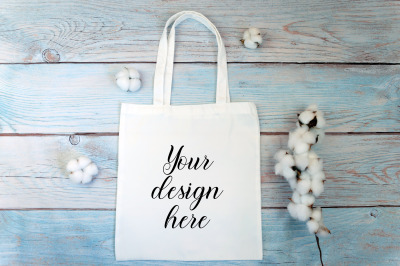 White tote bag Mockup with cotton flowers on a wooden background.