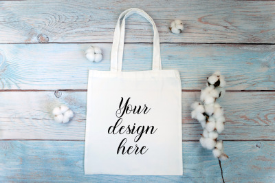 White tote bag Mockup with cotton flowers on a wooden background.