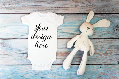 Baby Bodysuit mockup with toy on a wooden background.