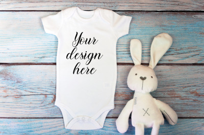 Baby Bodysuit mockup with toy on a wooden background.