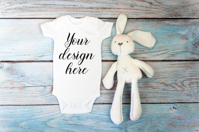 Baby Bodysuit mockup with toy on a wooden background.