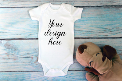 Baby Bodysuit mockup with toy on a wooden background.