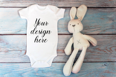 Baby Bodysuit mockup with toy on a wooden background.