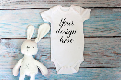 Baby Bodysuit mockup with toy on a wooden background.