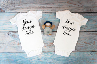 Twin baby bodysuit mockup on a wooden background.