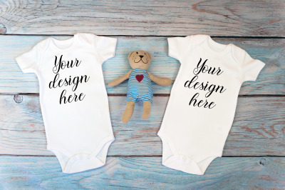 Twin baby bodysuit mockup on a wooden background.