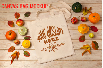 Rustic tote bag mockup with pumpkins and fall leaves.