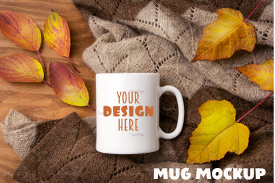 White coffee mug mockup with knitted blanket and fall colorful leaves.