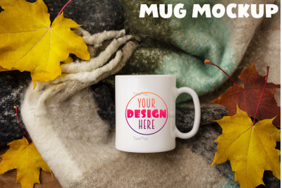 White coffee mug mockup with woolen scarf and fall maple leaves.