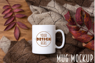 White coffee mug mockup with knitted blanket and red fall leaves.