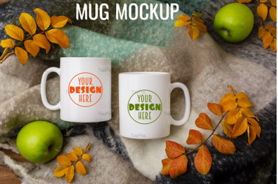 Two white coffee mug mockup with woolen scarf, apples and fall leaves.