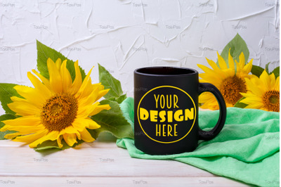 Black coffee mug mockup with green napkin and sunflowers.