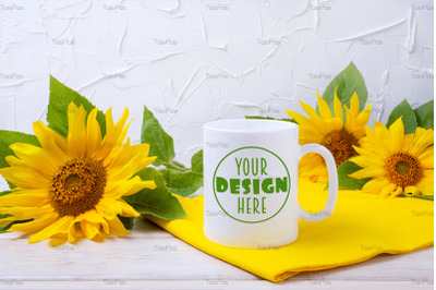 White coffee mug mockup with yellow sunflowers and napkin.