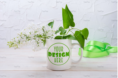 White coffee mug mockup with green ribbon and white lilac.