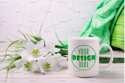White coffee mug mockup with lily and green scarf.