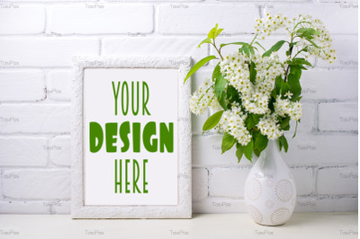 White frame mockup with blooming bird cherry in the decorated vase.
