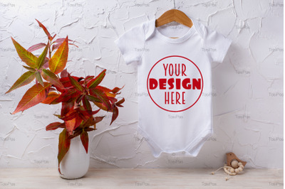 White baby short sleeve bodysuit mockup with red grass and wooden toy.